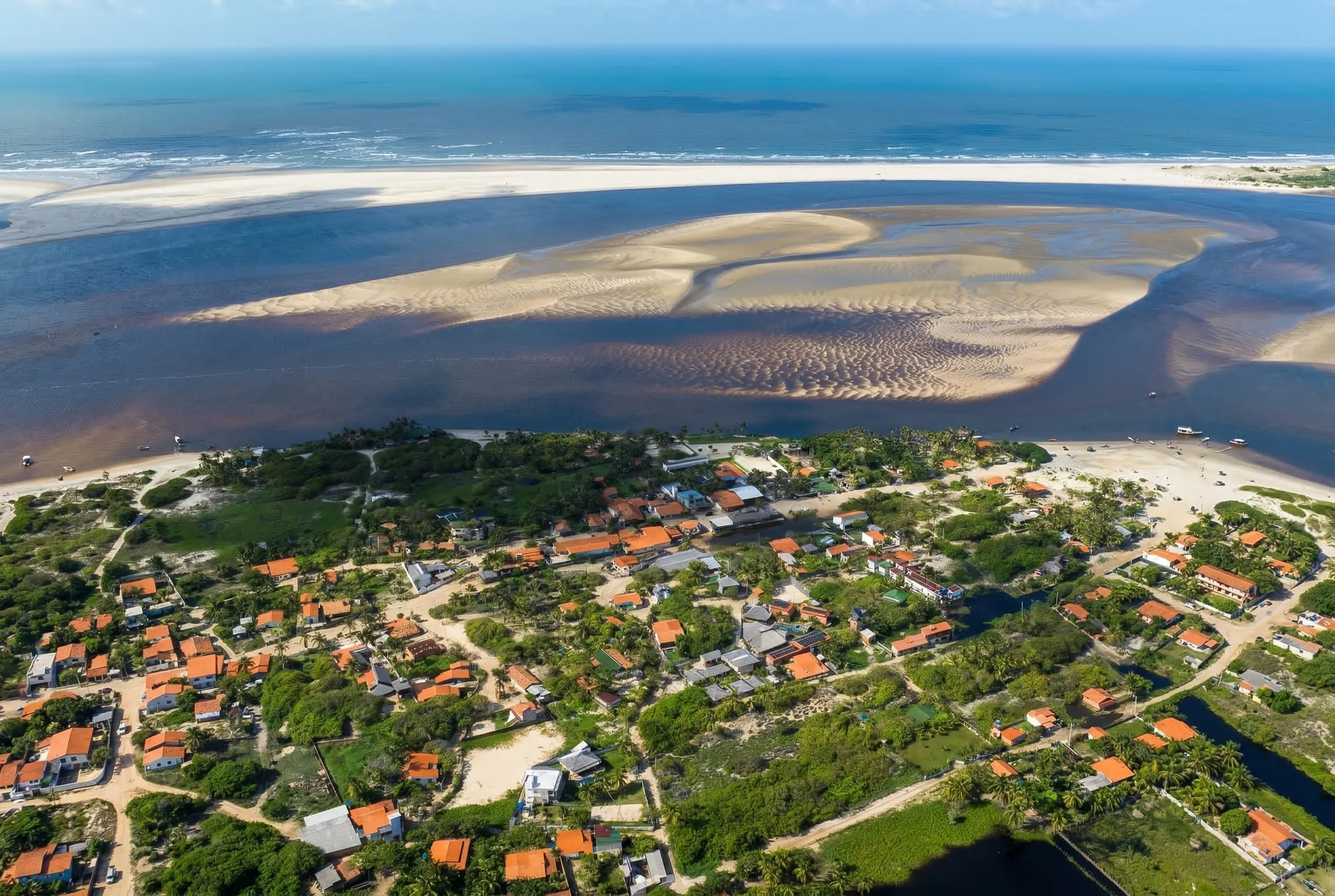 Vista aérea de Atins: casas junto à praia, bancos de areia, canais e o mar ao fundo.